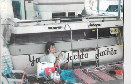 Hand lettering the back of a yacht while it is in the water.