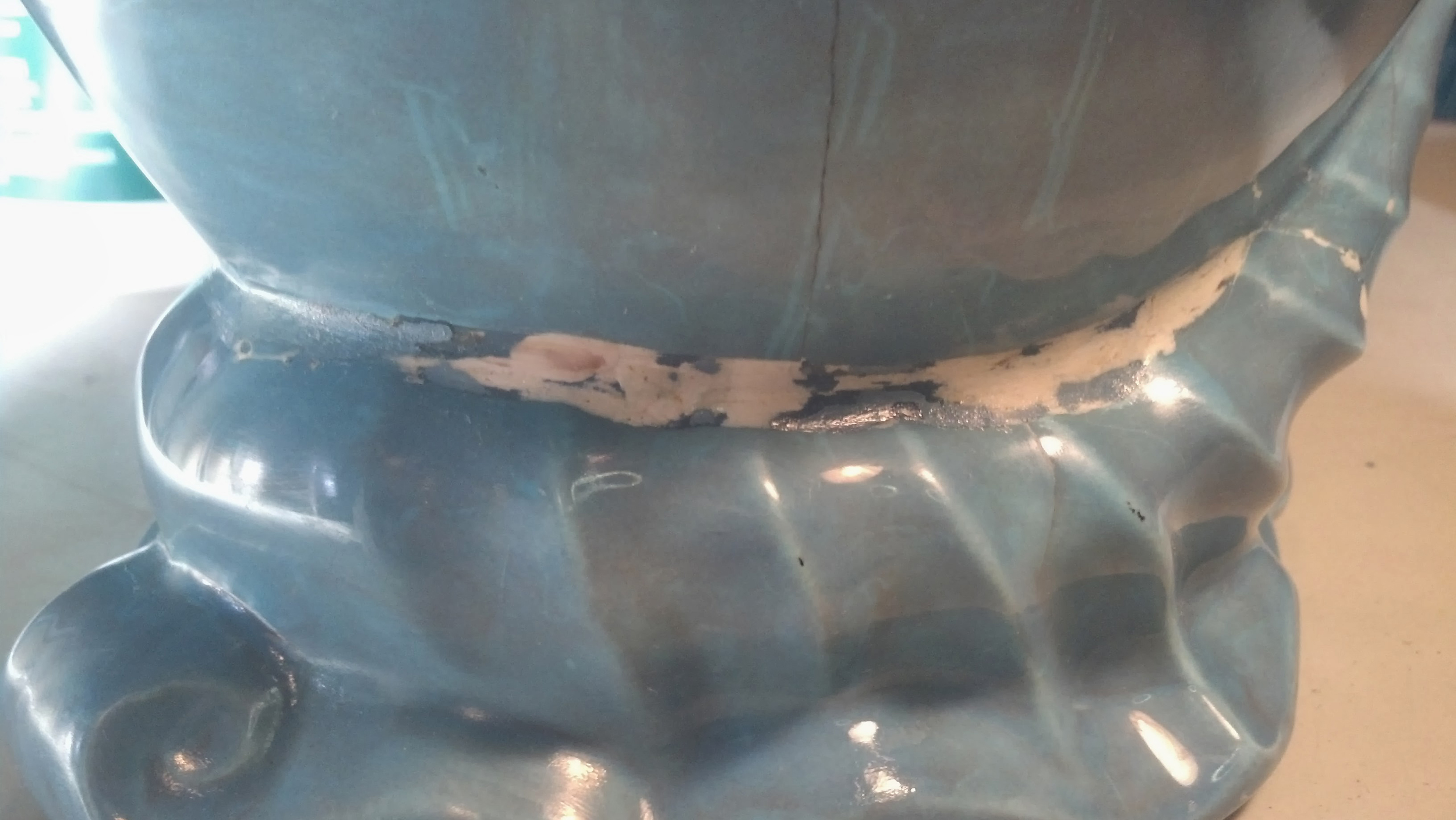 Damaged milk pitcher showing that it has been put back together.